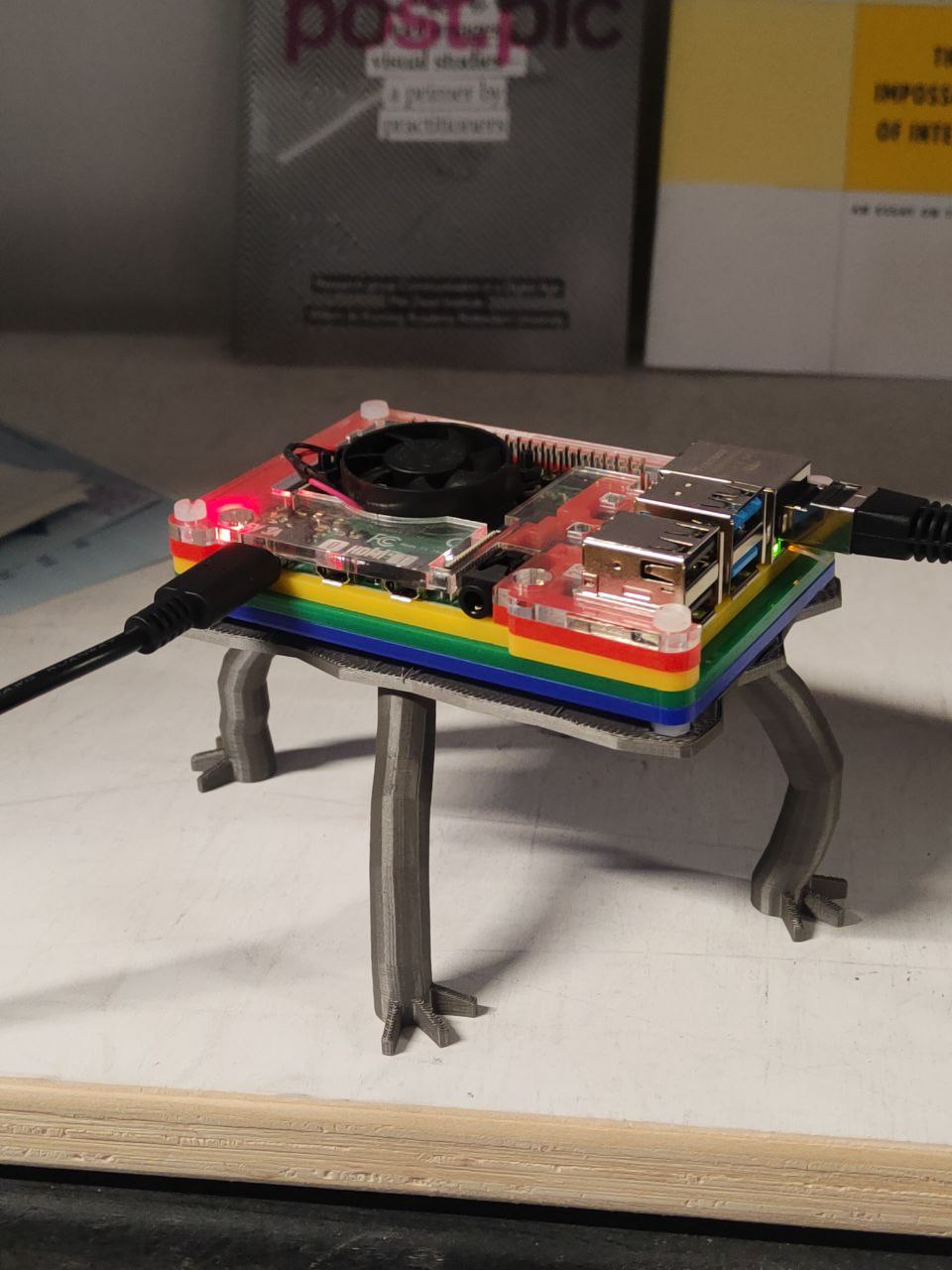 A raspberri pi 4 with a composable case made with four plastic layers: red yellow green and blue, and with custom 3d printed legs